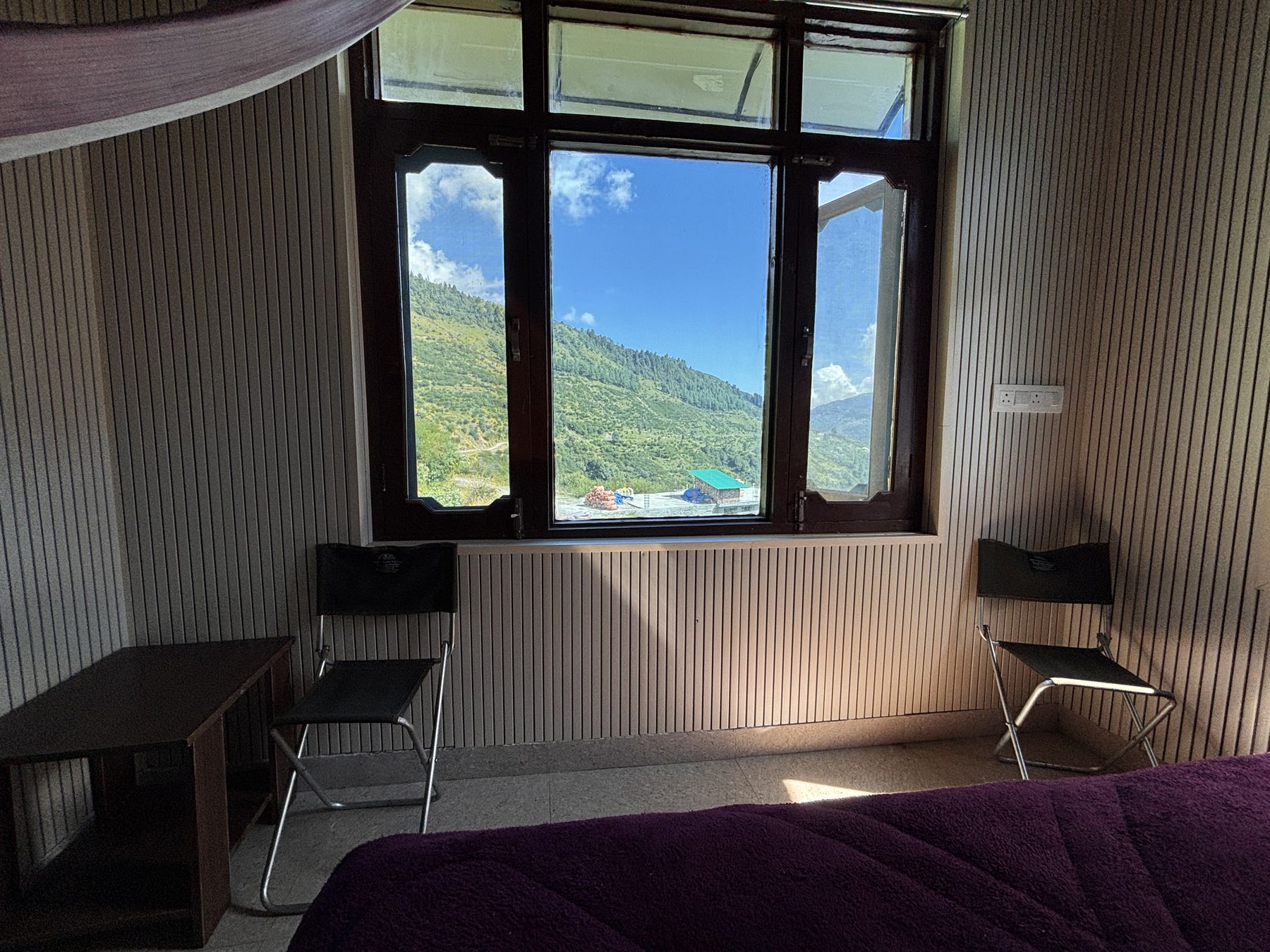 A room with a desk beside an open window looking onto the valley